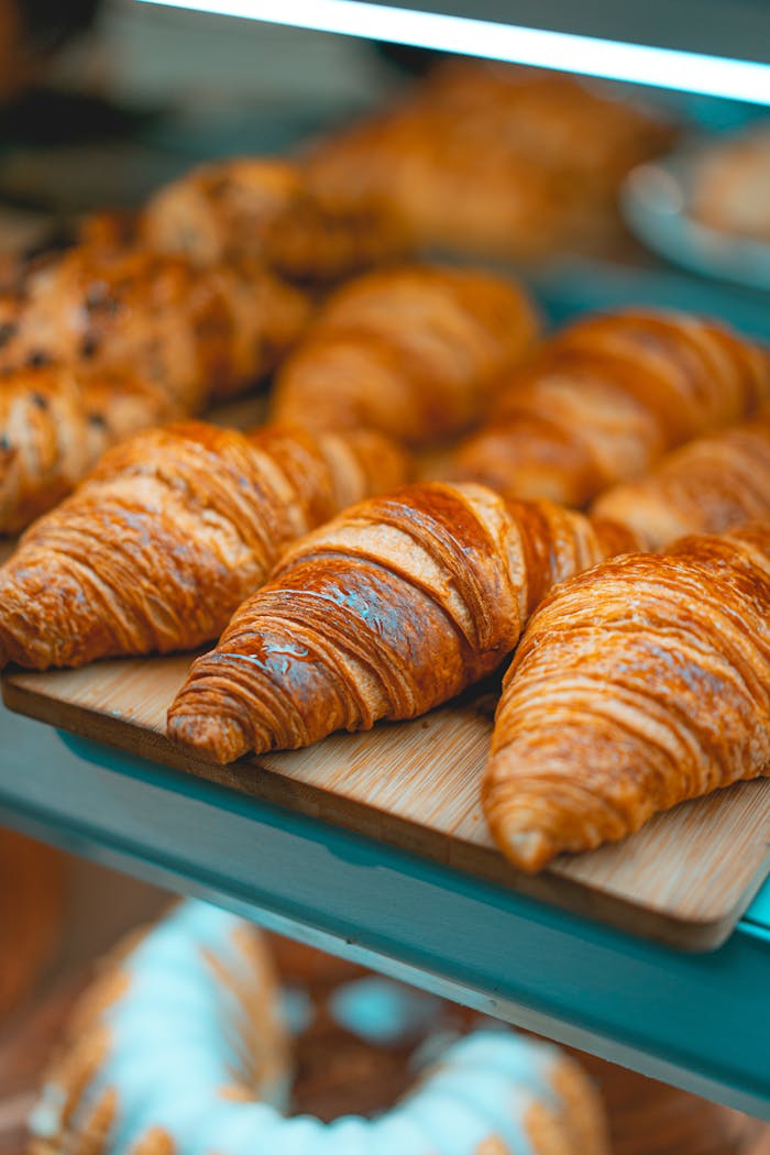 Nos Produits Delicious golden brown croissants arranged on a wooden board, perfect for breakfast.