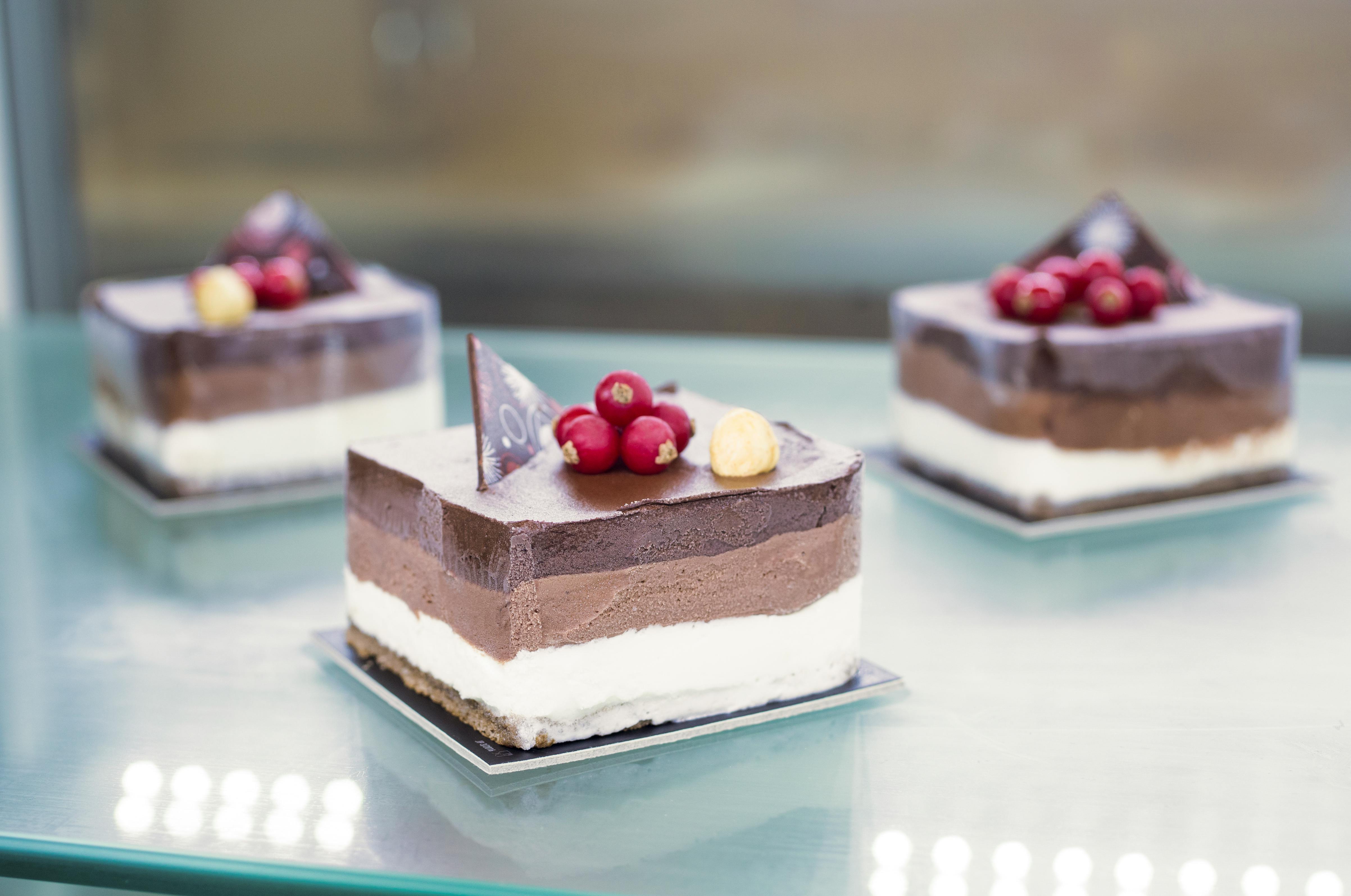 Nos Produits Delicious chocolate mousse cakes with berries and nuts on a glass surface.
